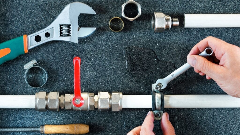 Plumber repairing a pipe valve with an adjustable wrench in Vero Beach