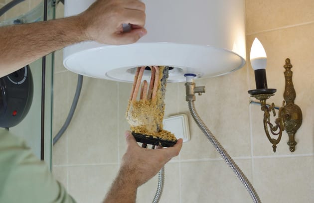 Technician removing mineral buildup from a water heater in Vero Beach