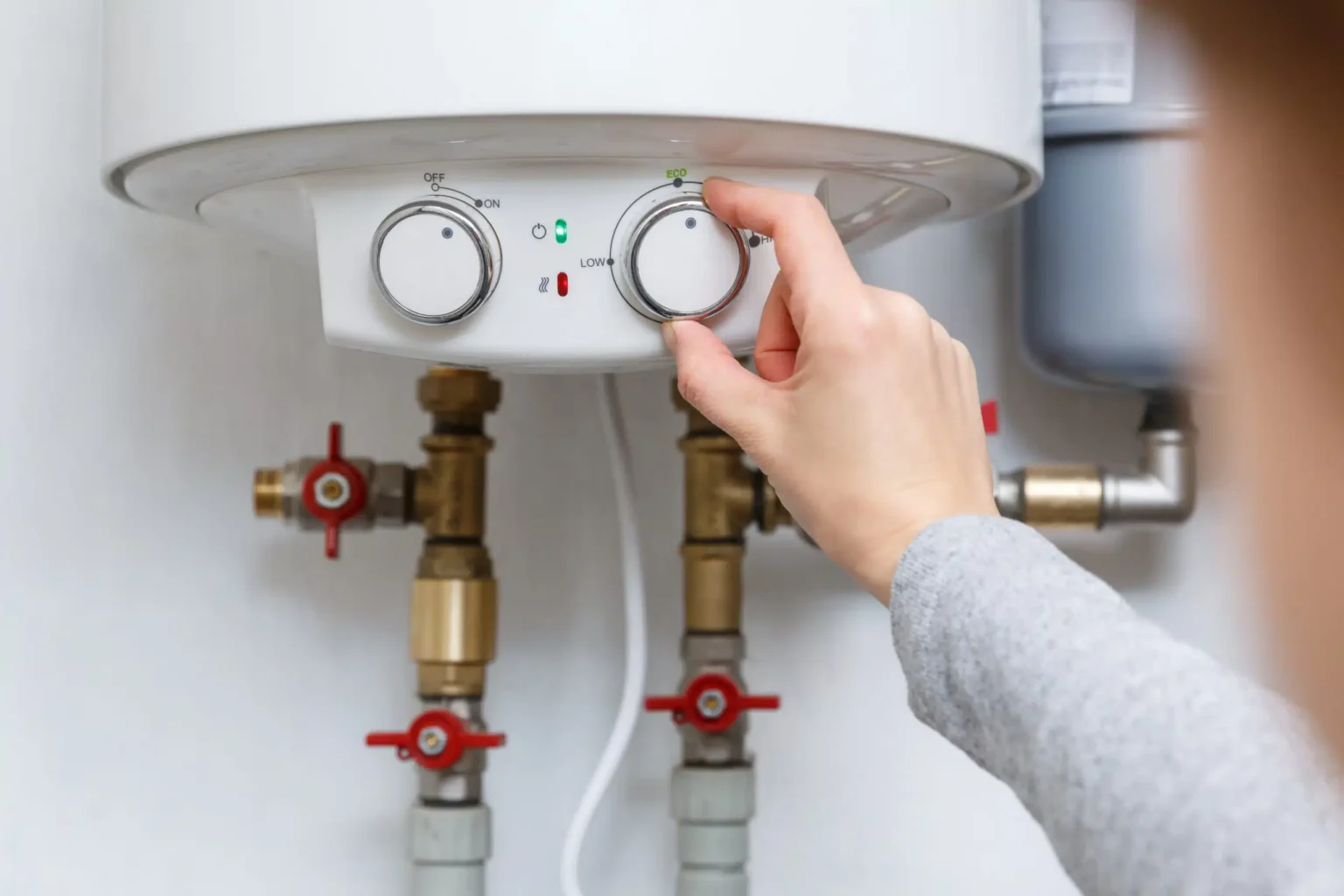 Homeowner adjusting the temperature controls on a water heater in Vero Beach